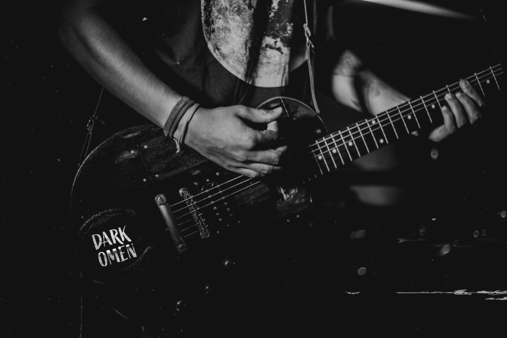 Close-up of a guitar with a “Dark Omen” sticker, part of fictional band merch created for L.A. Cannon’s author brand.